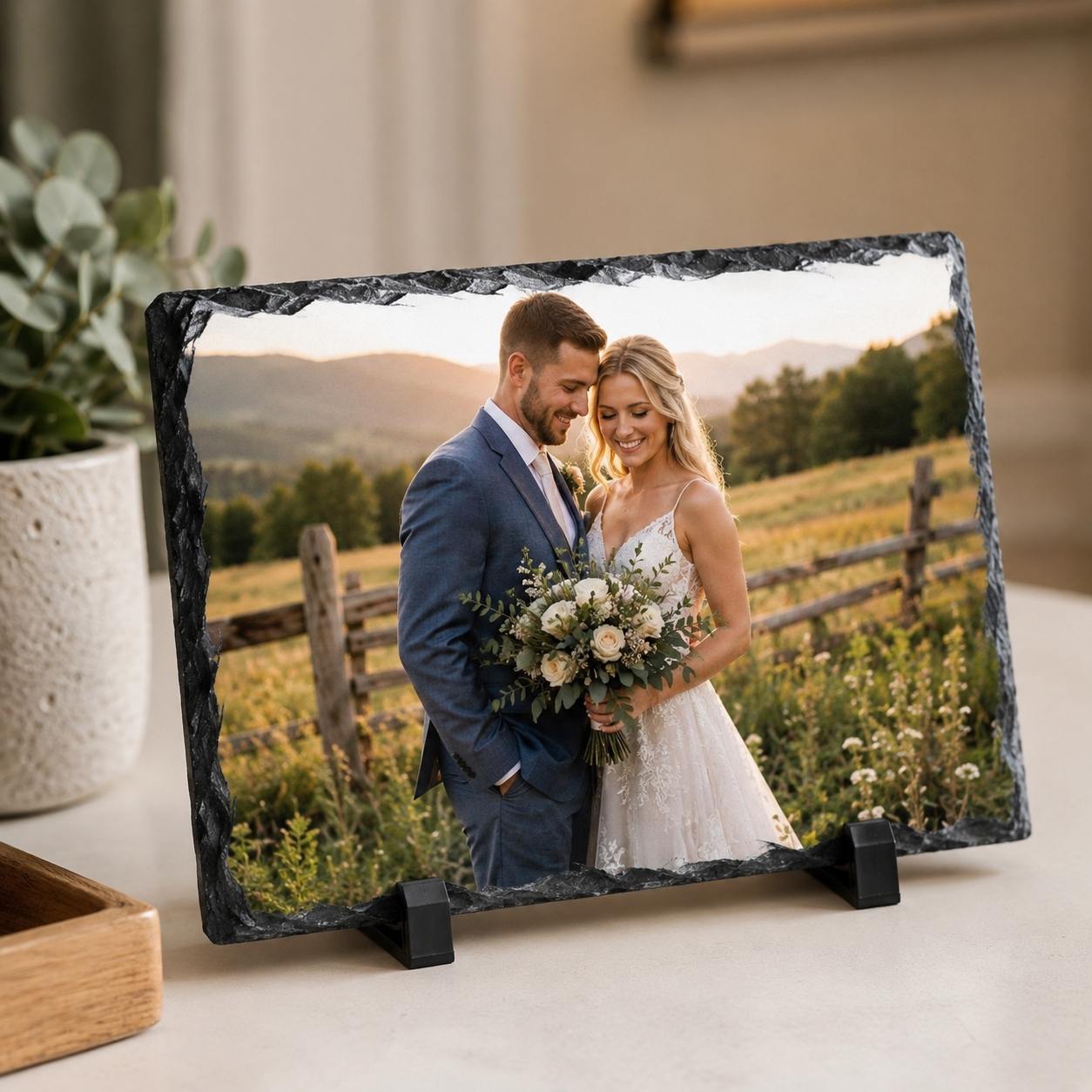 Bride and groom embracing at a countryside sunset, printed on a natural-edge slate on its stand