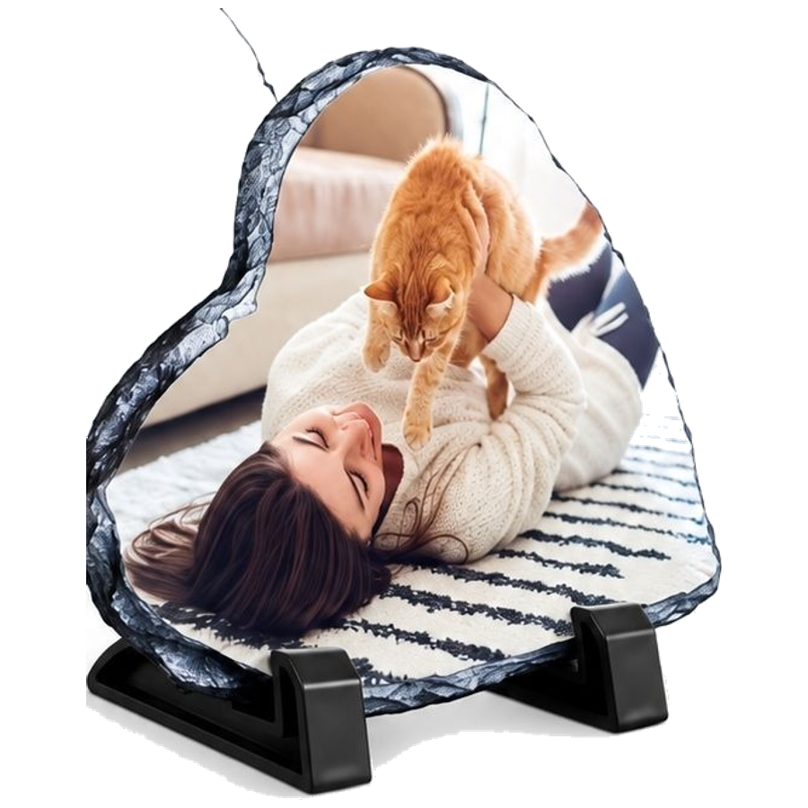 A heart-shaped photo keepsake on its small black stand, a photograph of a woman holding her orange cat printed into the natural stone